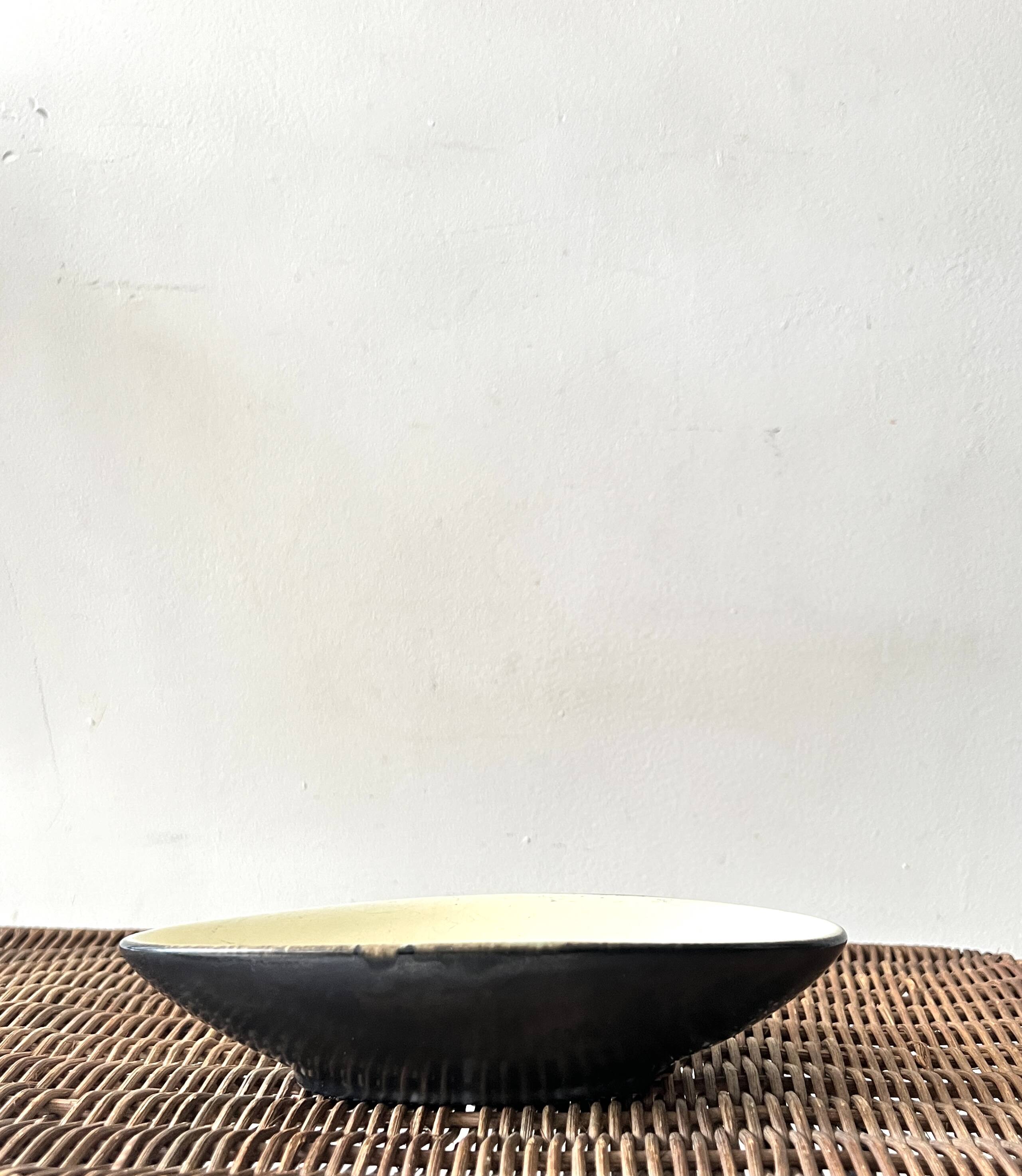 Pale yellow and black ceramic bowl / empty pocket signed by the artist