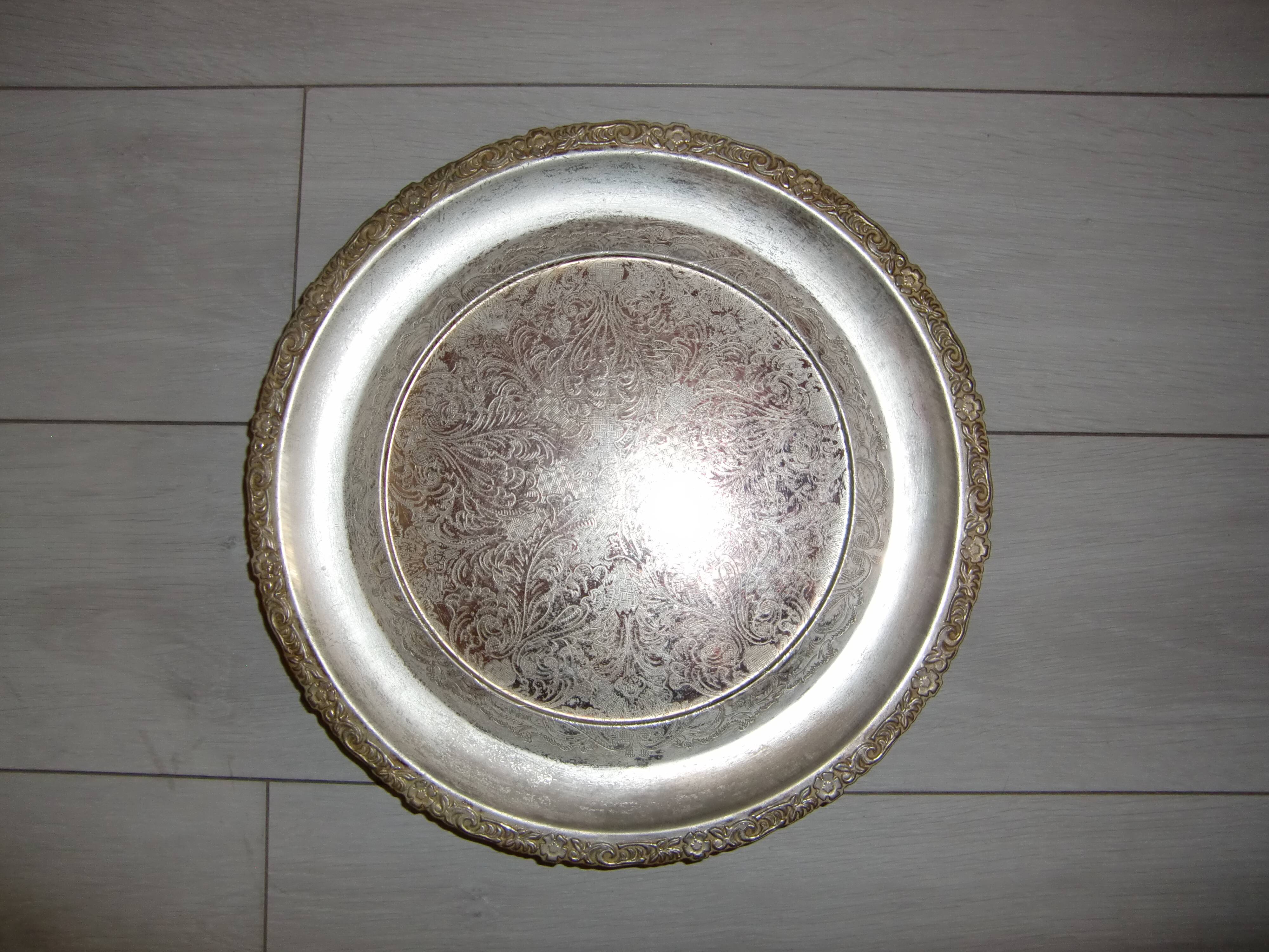 Large silver metal tray raised by a central foot