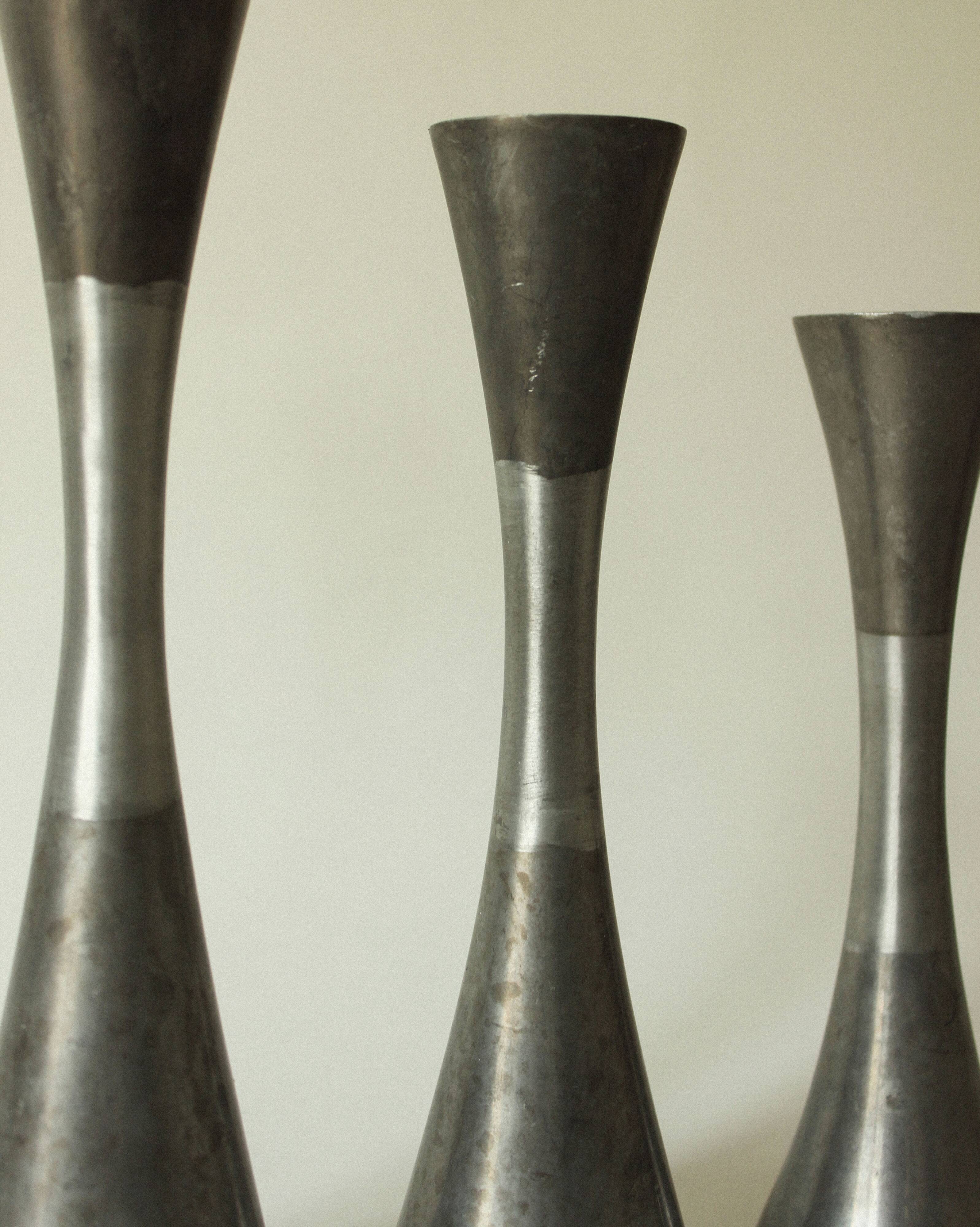Set of three diabolo-shaped candle holders made of cast steel.