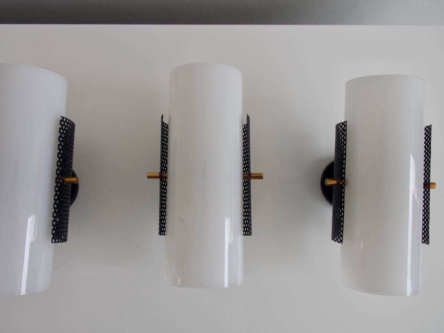 Set of four wall lights in white plexiglass and perforated black metal.