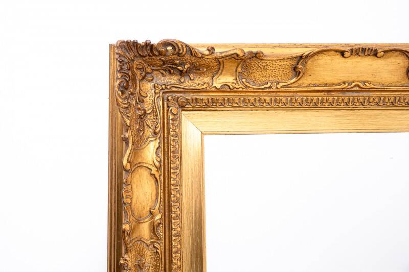 A mirror with a golden, richly carved frame.