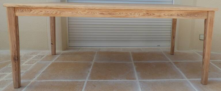 Large natural wood table with rectangular top supported by legs