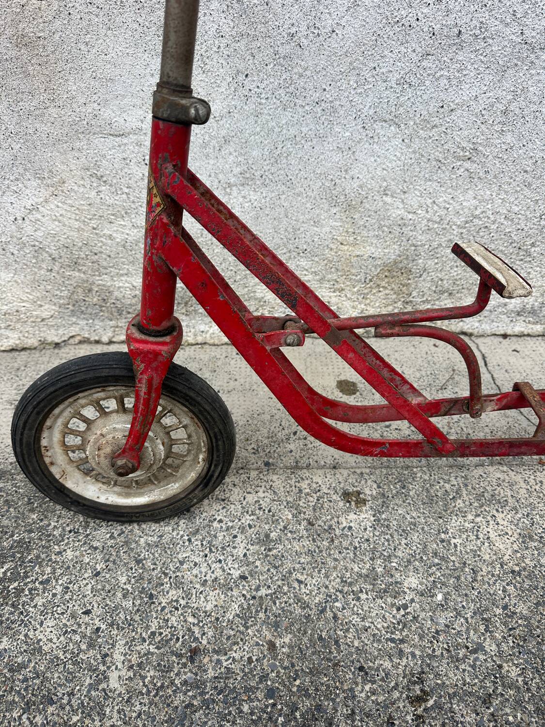 Trottinette rouge ancienne à pédale et chaîne