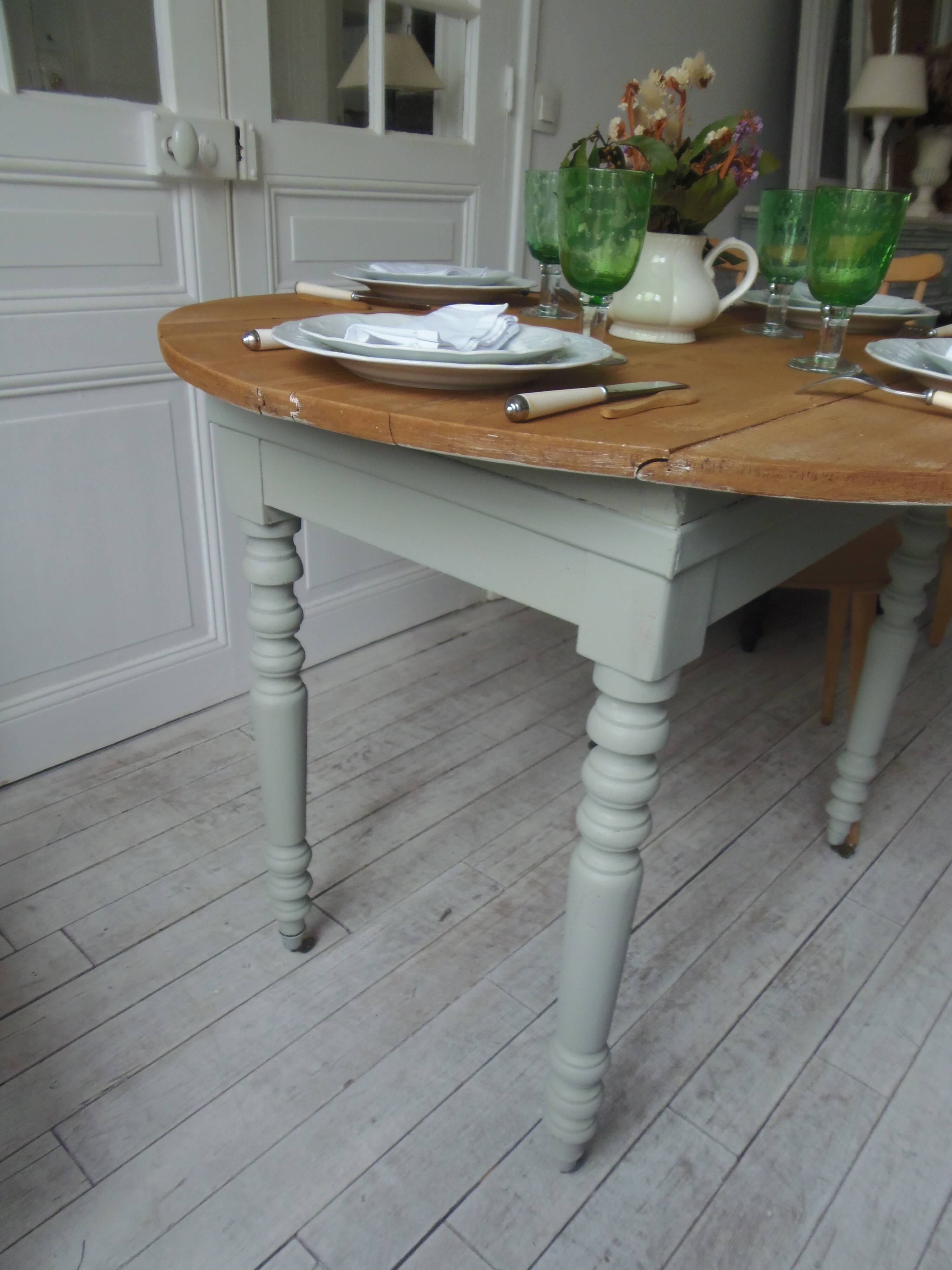 Raised walnut table with drop-leaf top, base on verdigris castors.