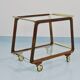 May include: A mid-century modern bar cart with a dark wood frame and two c