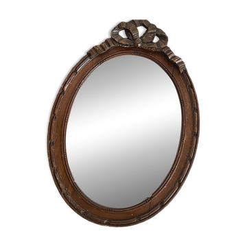 Oval mercury mirror in carved wood with ribbon bow decoration 37X52.