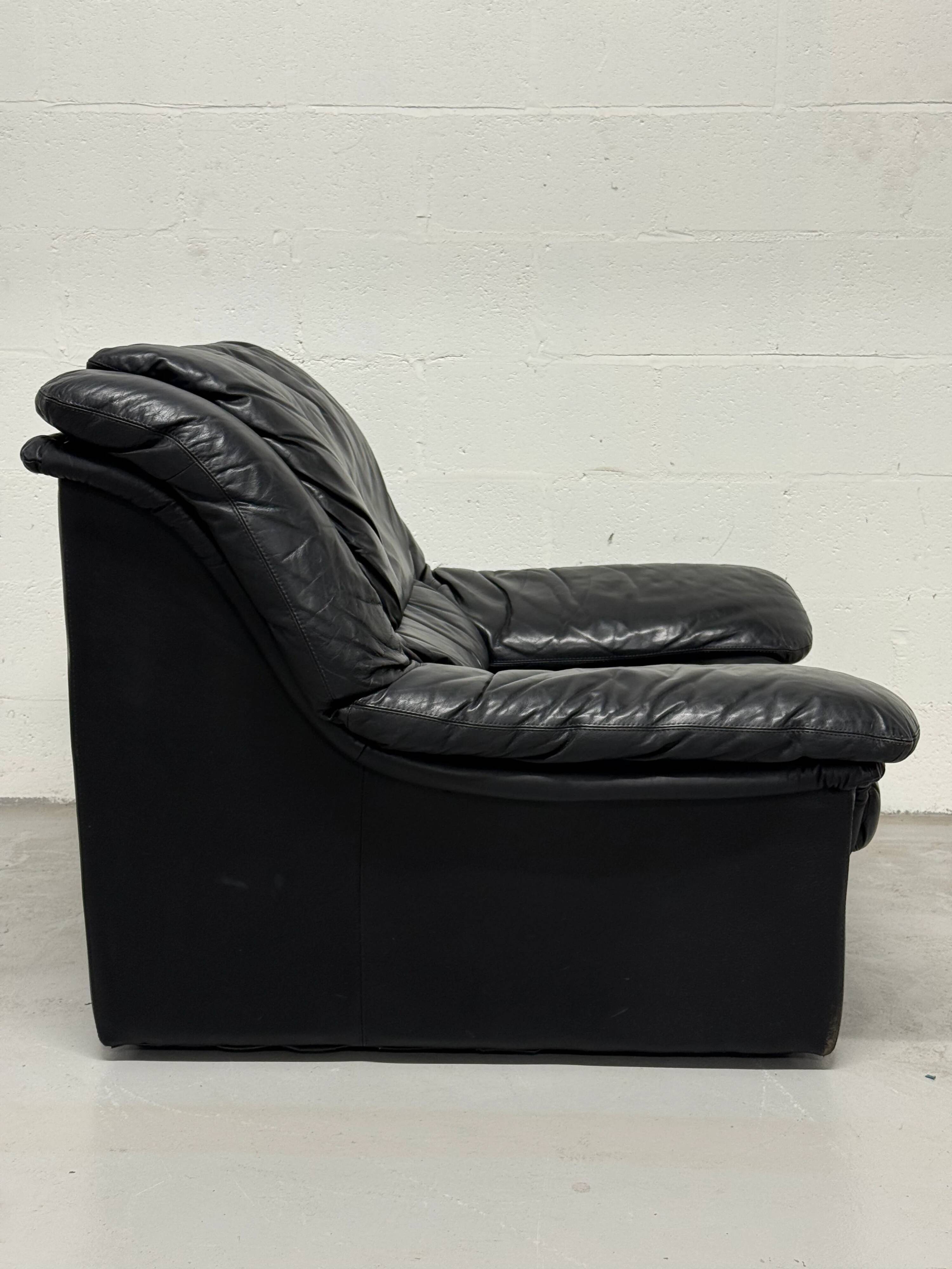 Vintage black leather lounge chair — low postmodern club chair from the space age.