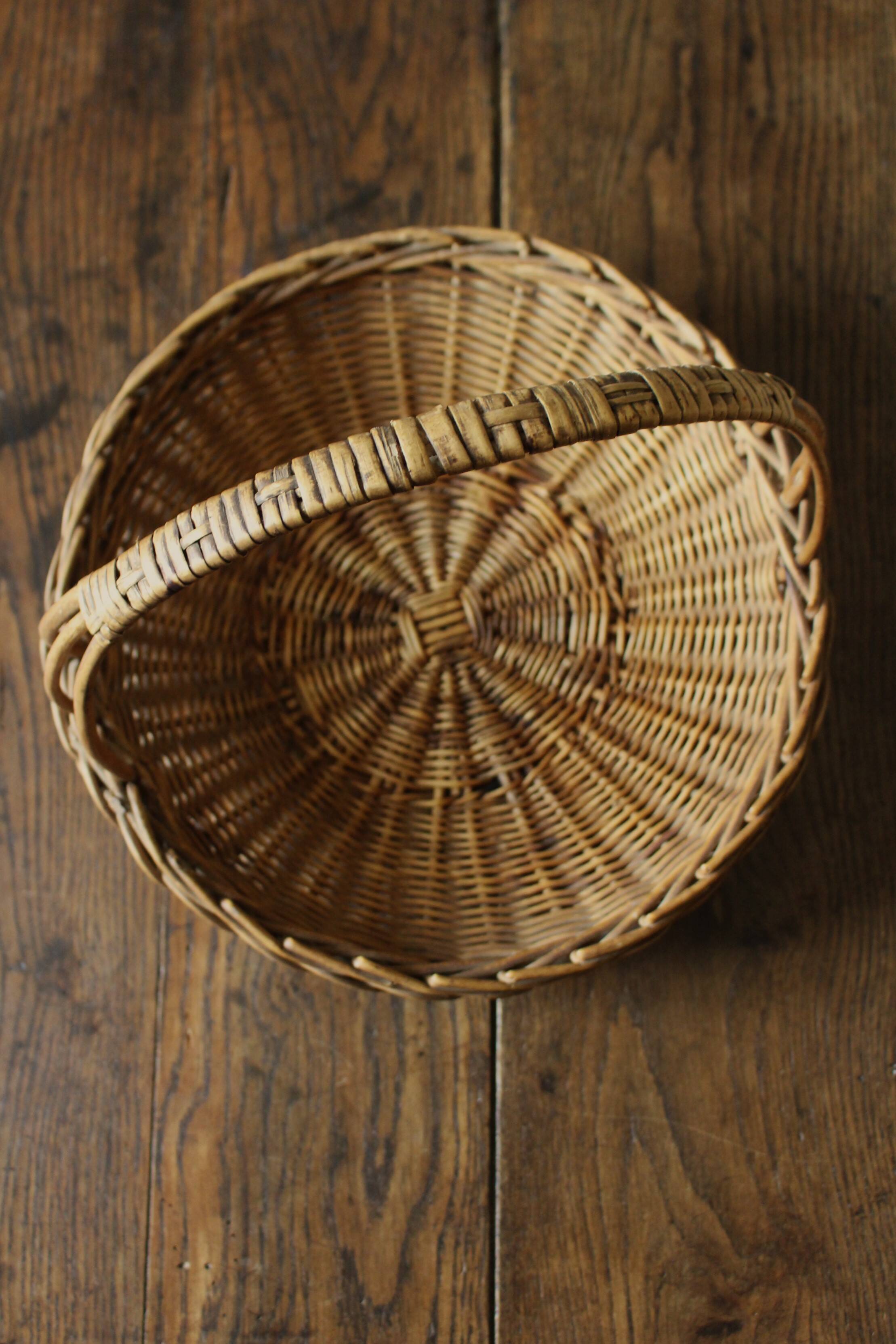 Round wicker basket with a rigid handle.