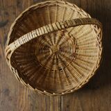Round wicker basket with a rigid handle.