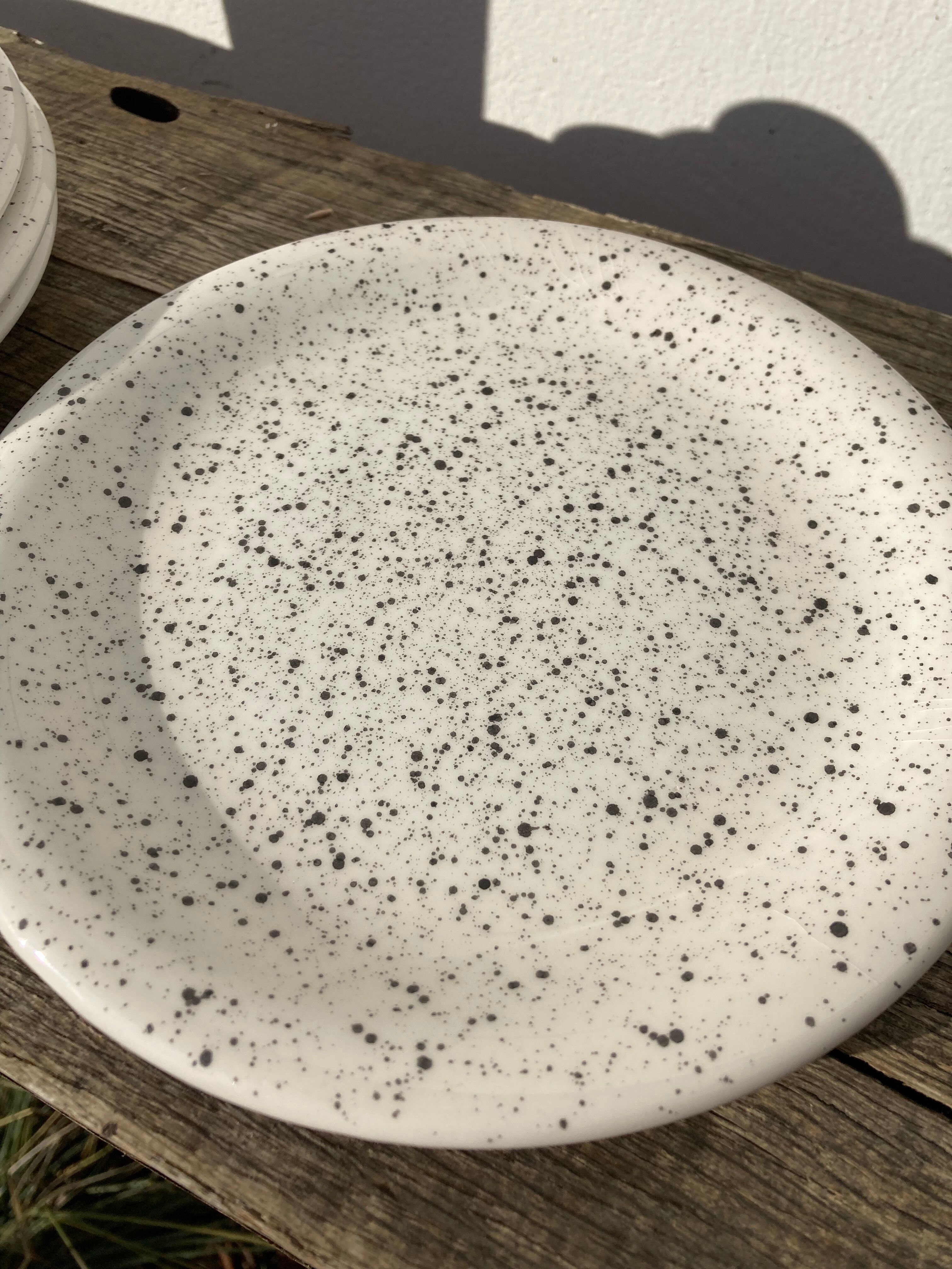 4 black speckled dessert plates on a vintage white background