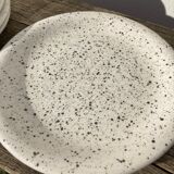 4 black speckled dessert plates on a vintage white background