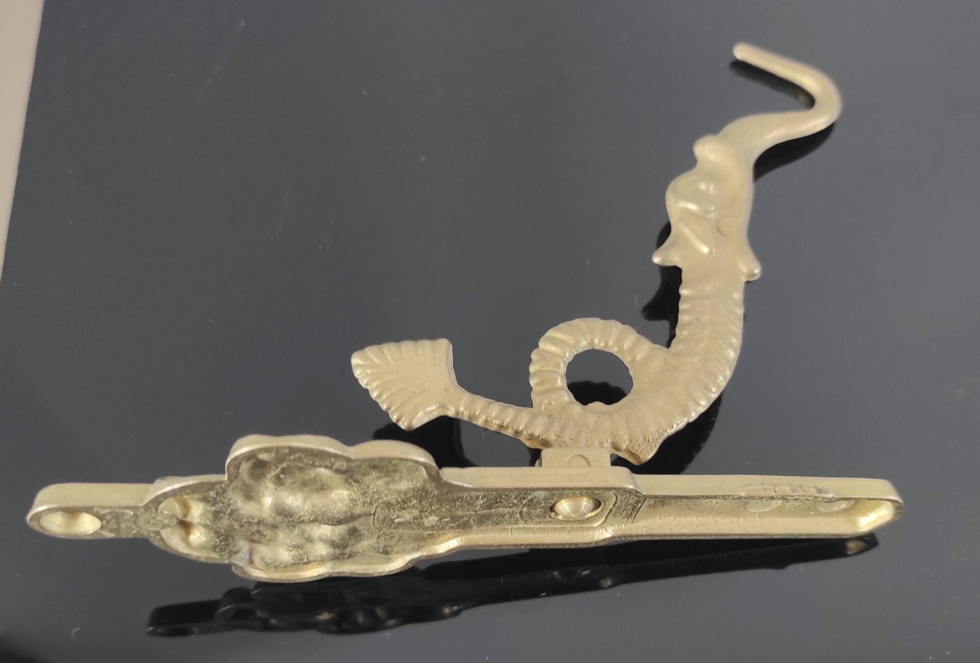 Vintage brass coat hook with marine creature motif and medallion.