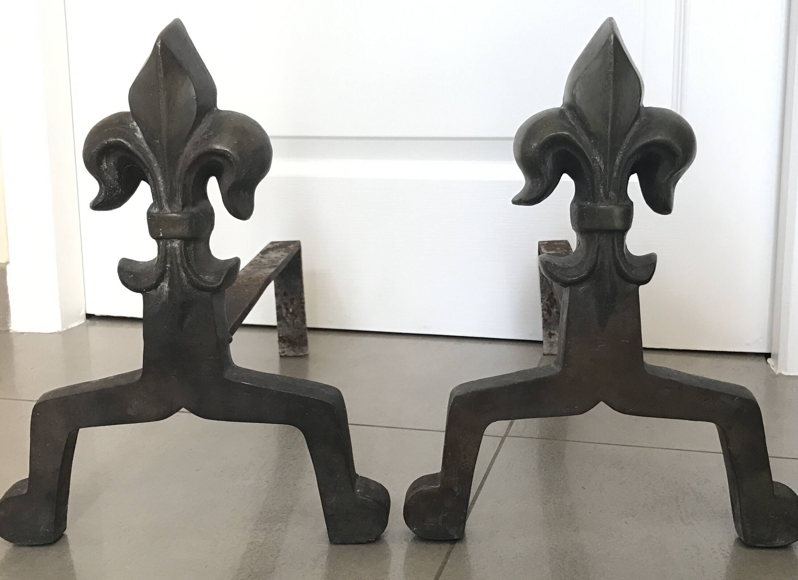 Pair of bronze fireplace firedogs with fleur-de-lys decor, art deco