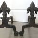 Pair of bronze fireplace firedogs with fleur-de-lys decor, art deco