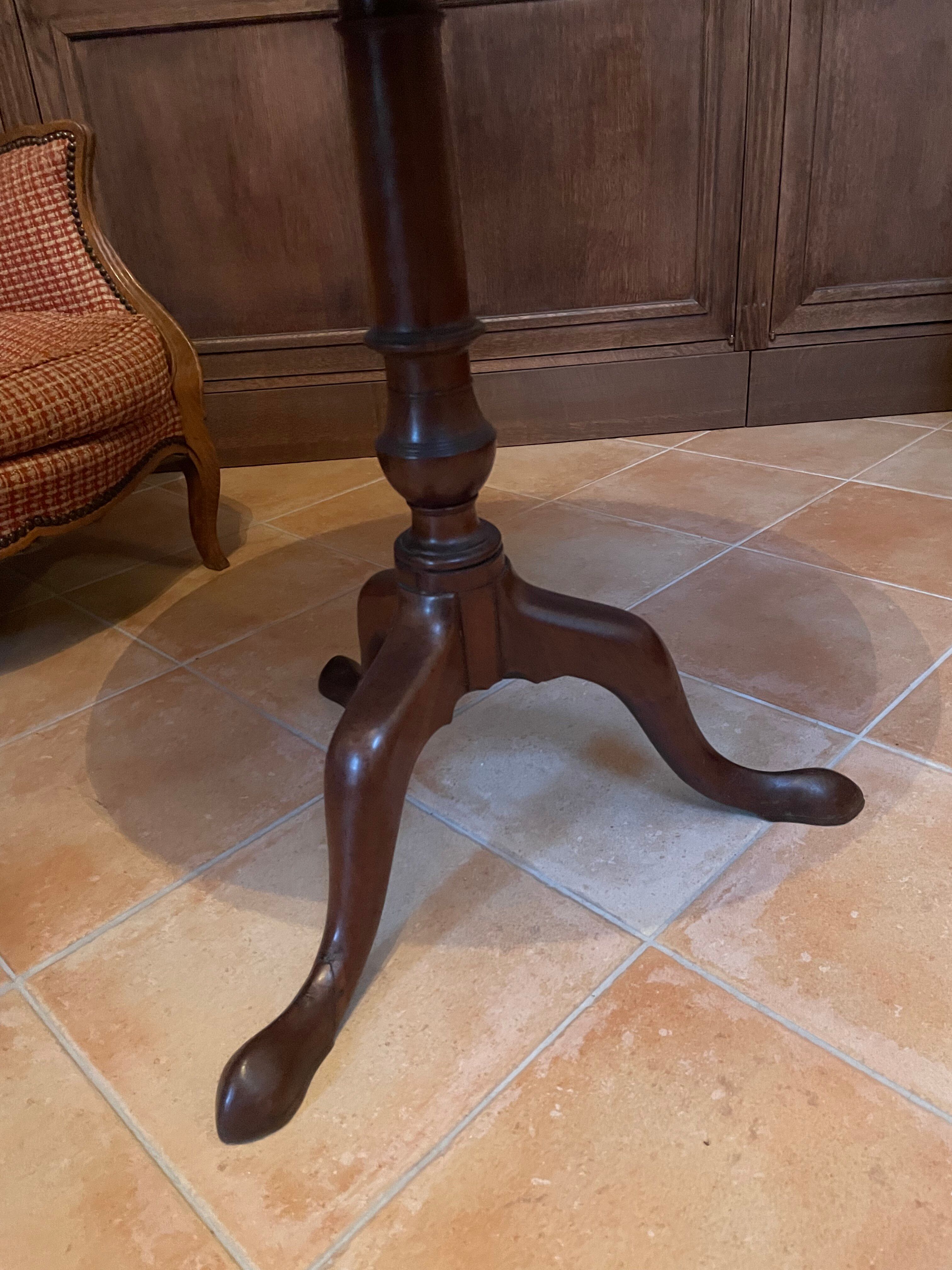 Foldable tripod side table in carved mahogany with brass trim.