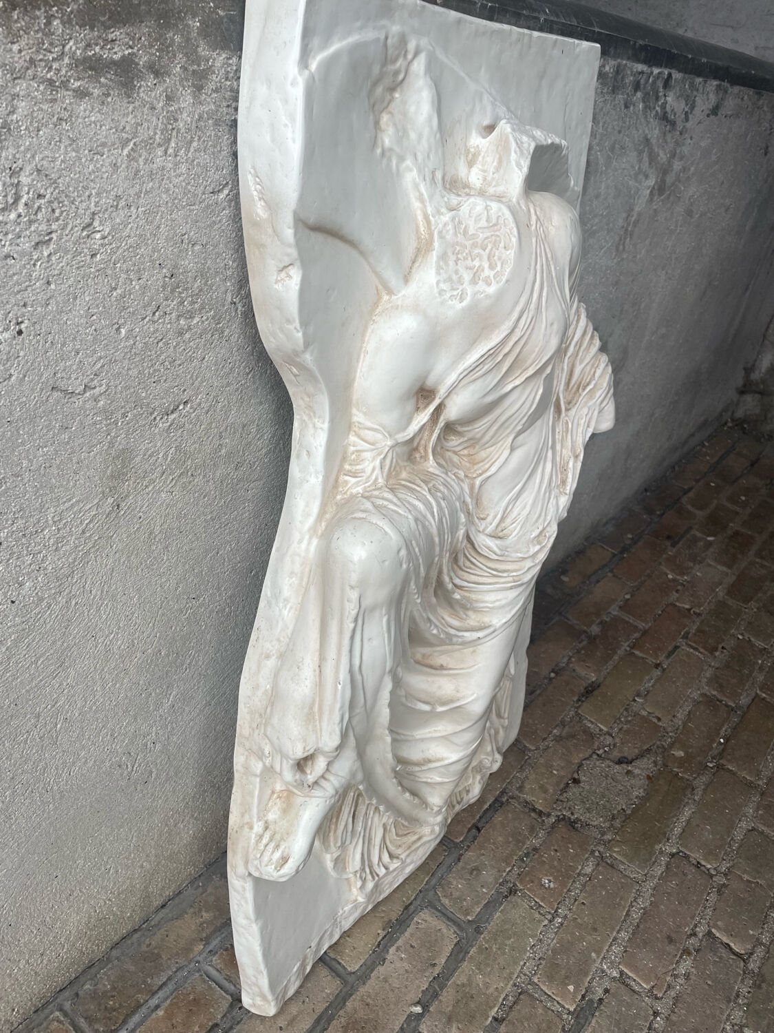 Ancient plaster bas-relief of Nike fastening her sandal.