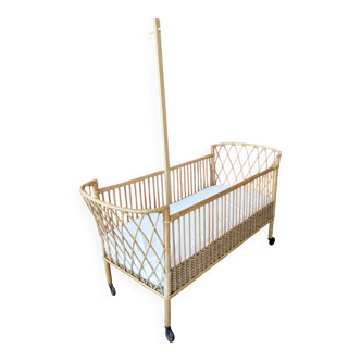 Newly refurbished rattan baby cot, with an oak arrow for a mobile.