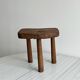 Antique three-legged stool made of raw solid wood.