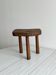 Antique three-legged stool made of raw solid wood.
