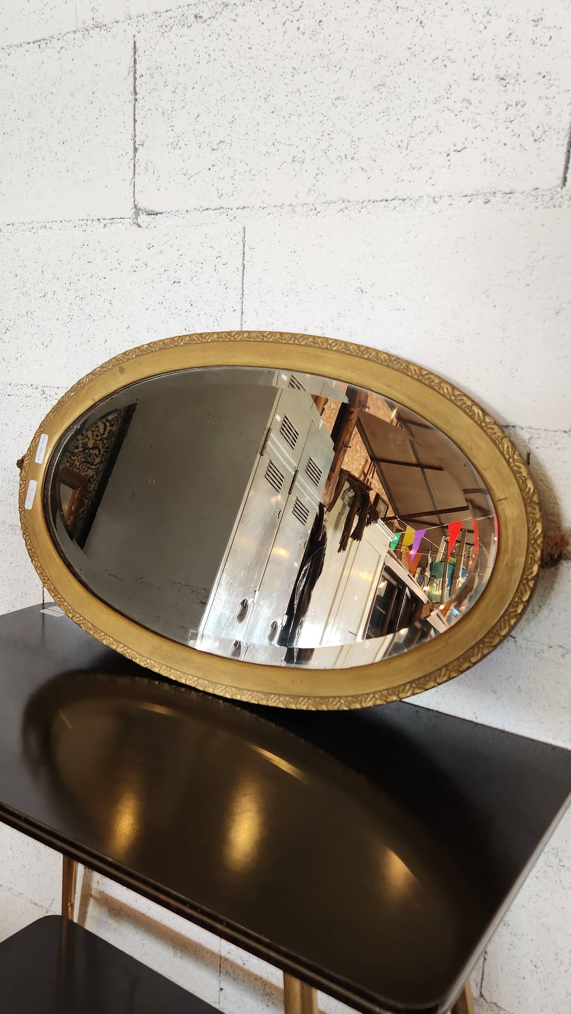 Antique oval mirror with a gilded frame, bevelled glass.