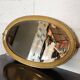 Antique oval mirror with a gilded frame, bevelled glass.