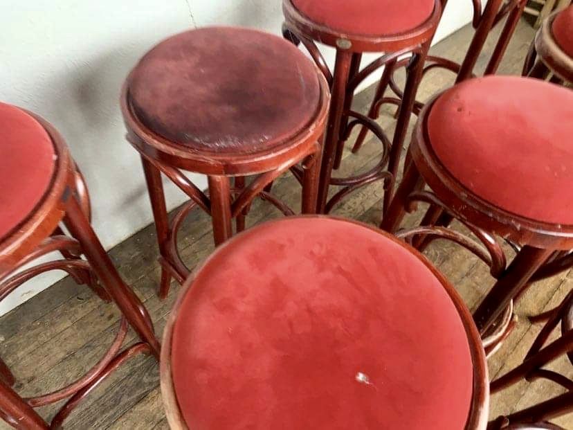 Series of 9 bistro bar stools in curved wooden restaurant sitting red fabric