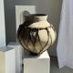 Very large light grey terracotta pot with handles and rattan crossbars.