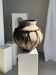 Very large light grey terracotta pot with handles and rattan crossbars.