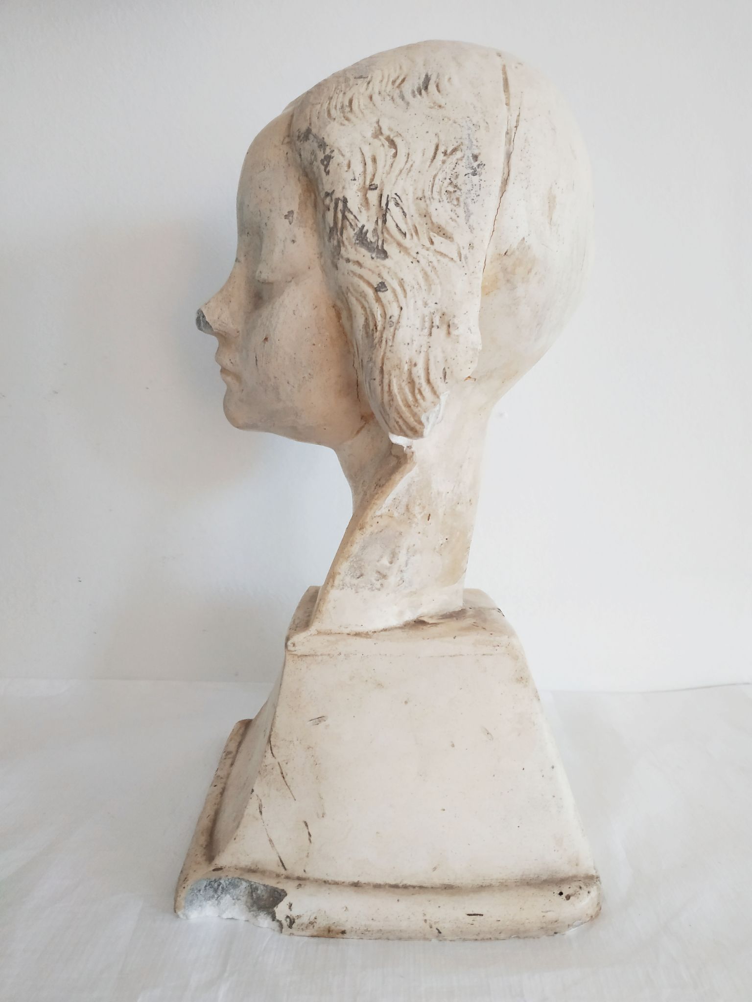 Bust of woman in plaster on pedestal with inscription