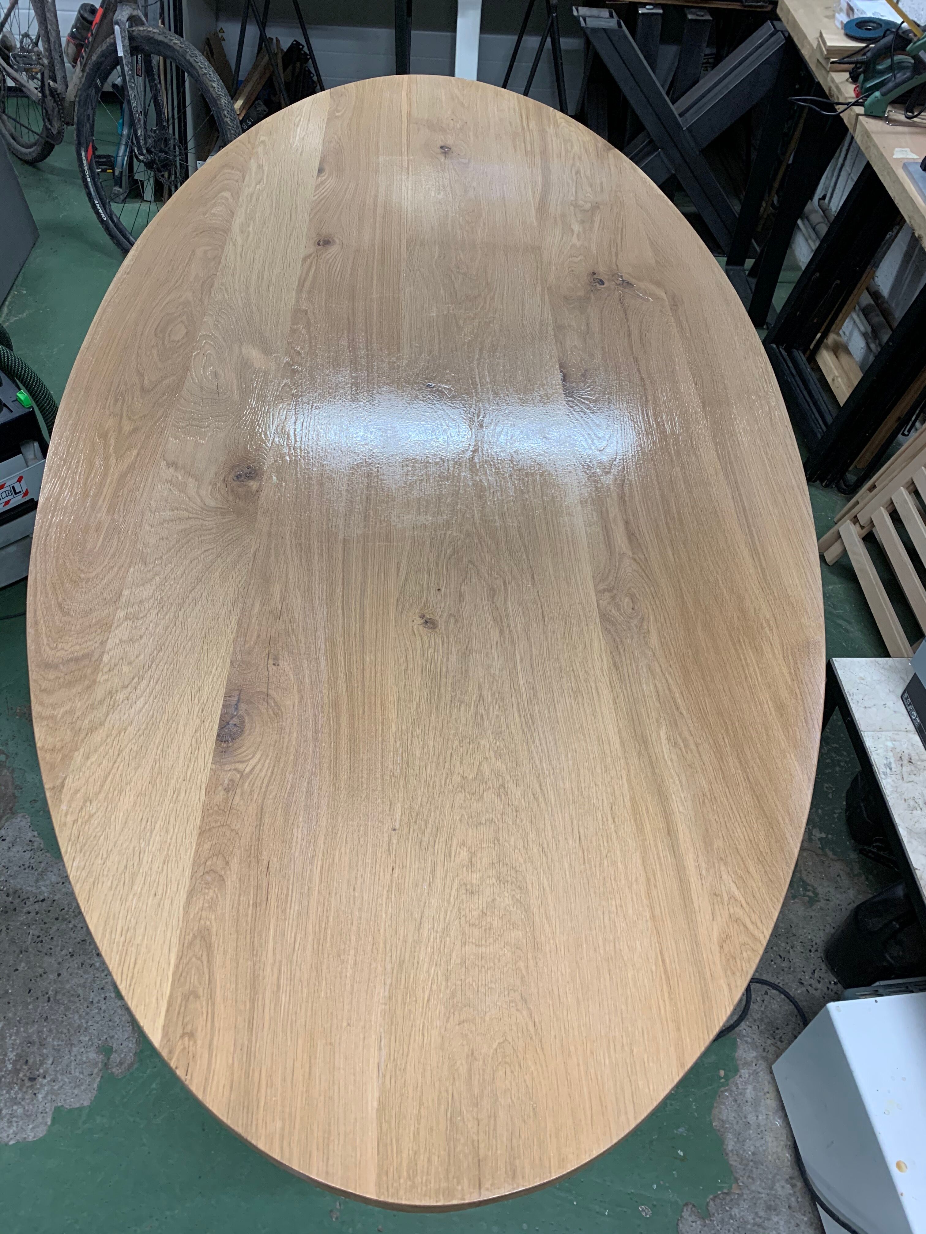 Oval table in solid oak refined edges with central foot in black metal
