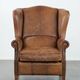 Fauteuil à oreilles de style anglais couleur cognac en cuir de vache.