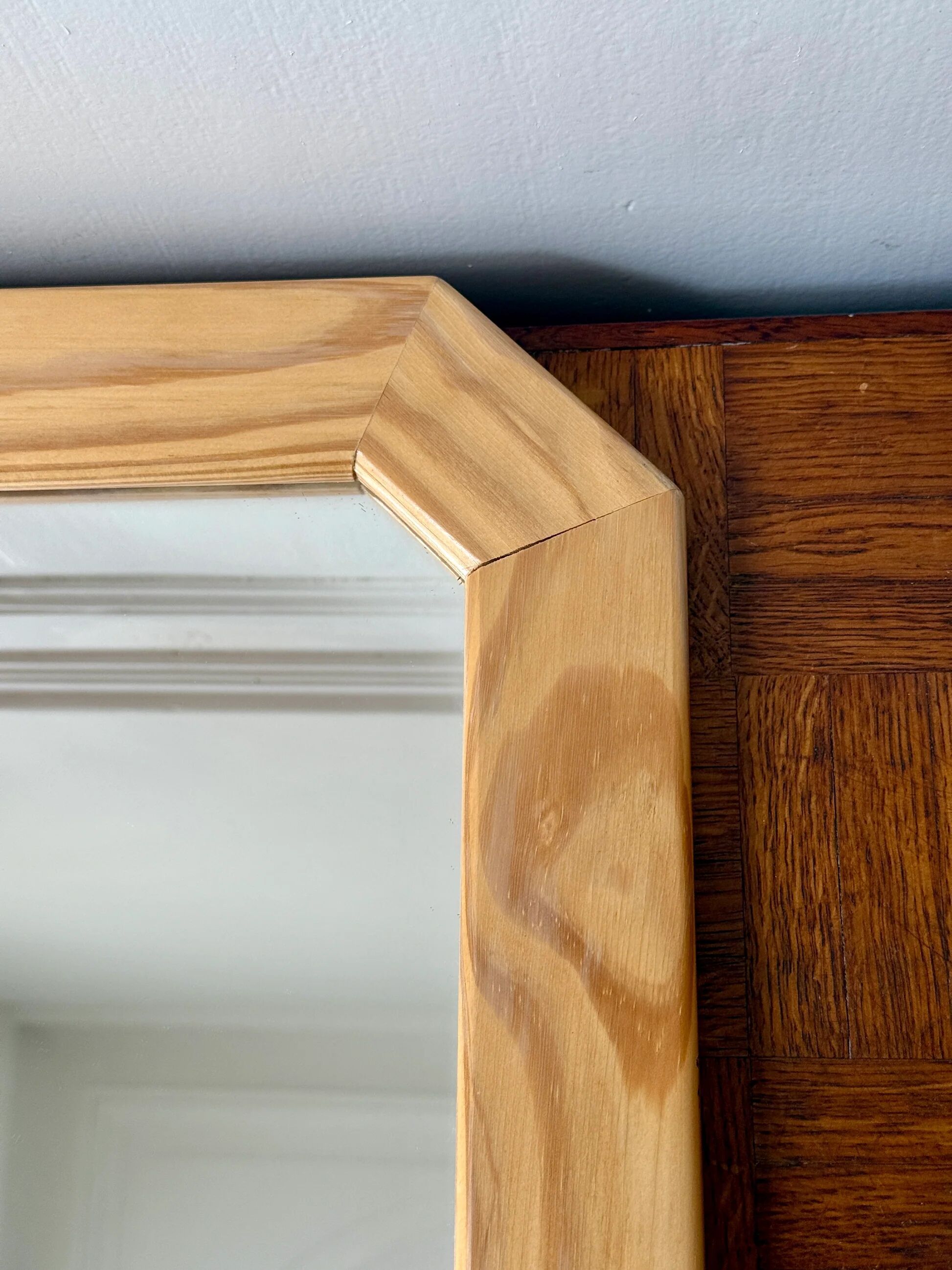Octagonal mirror in light wood with grooves.