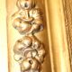 Miroir rectangulaire en bois doré à décor en relief de fleurs.