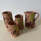 Artisanal pottery set in red clay with harmonious plant motifs