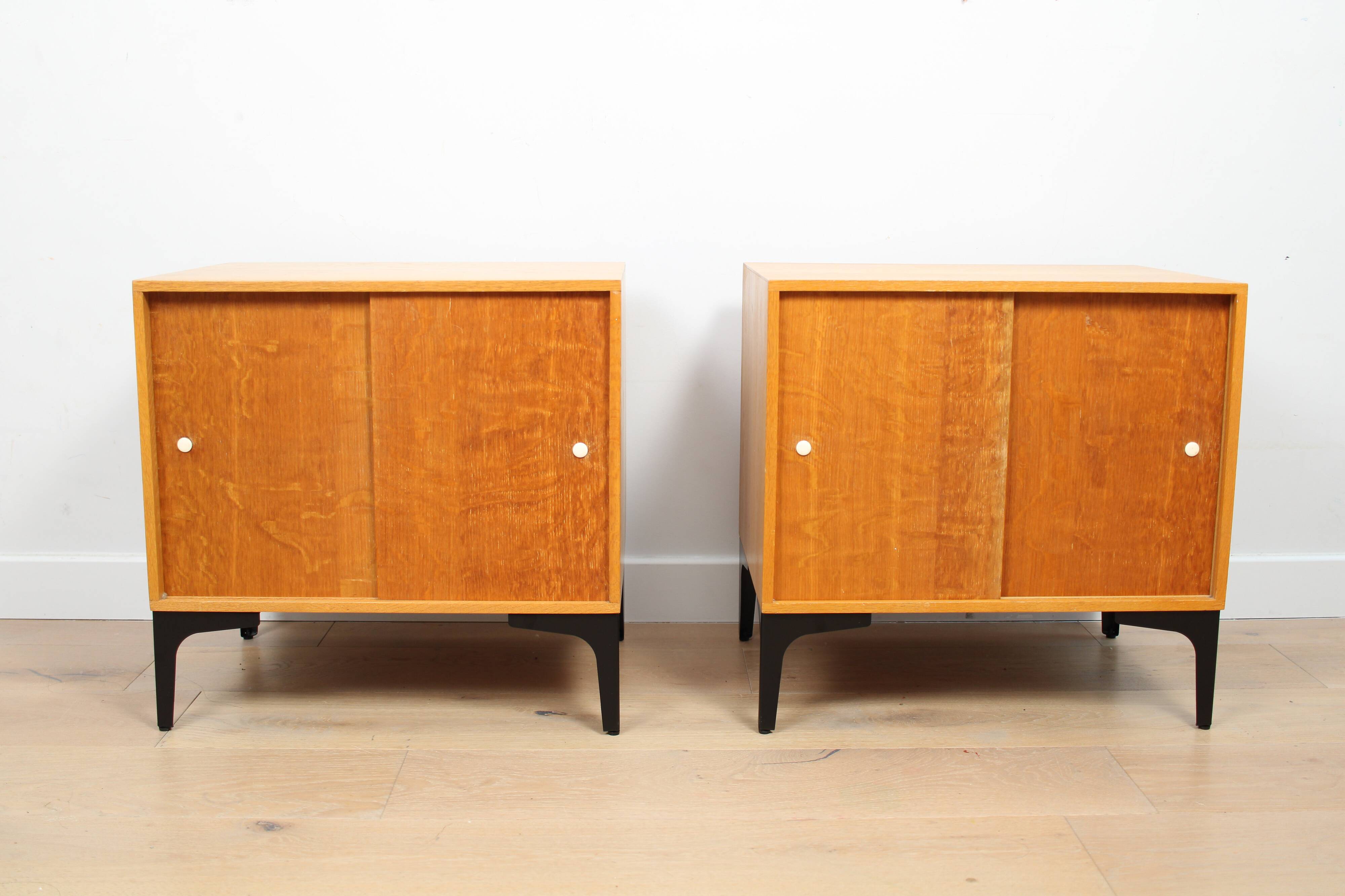 A pair of vintage mid-century bedside tables with oak sliding doors