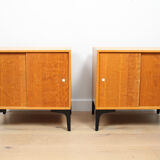 A pair of vintage mid-century bedside tables with oak sliding doors
