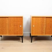 A pair of vintage mid-century bedside tables with oak sliding doors
