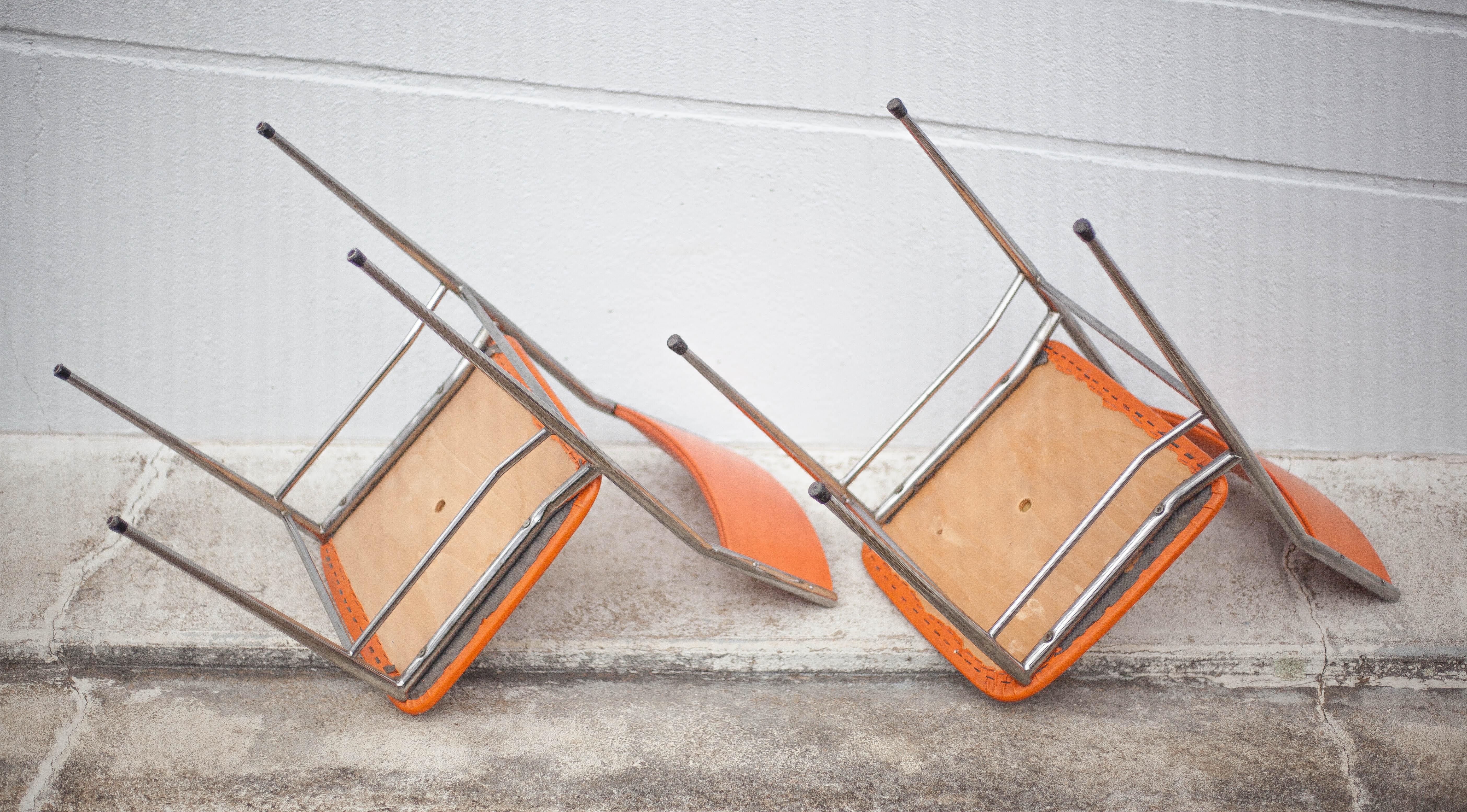 Pair of chrome metal chair and orange skai