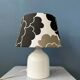 Small Space Age table lamp with a porcelain base and black and white flower shade.