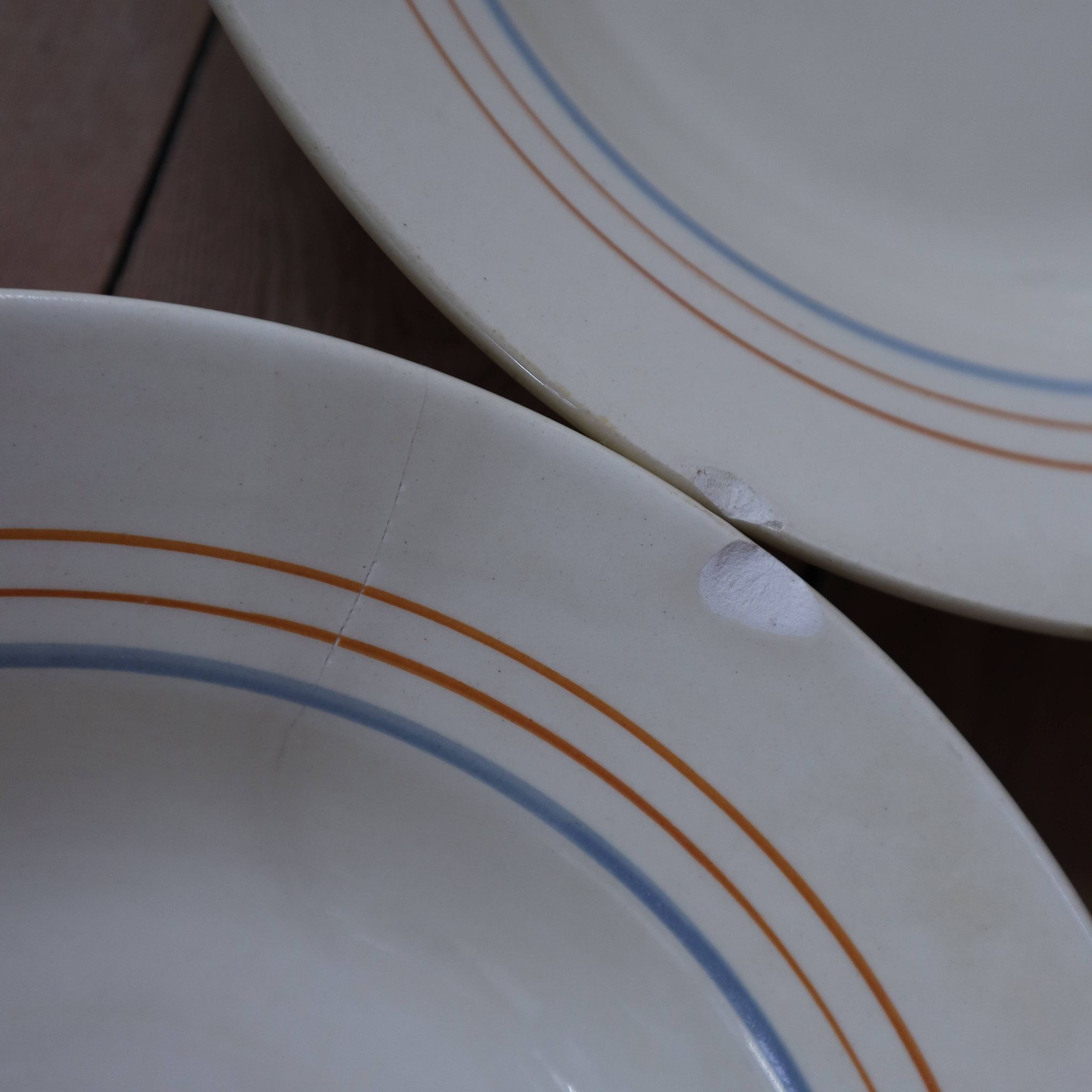 6 old cream-coloured deep plates with blue/orange trim.