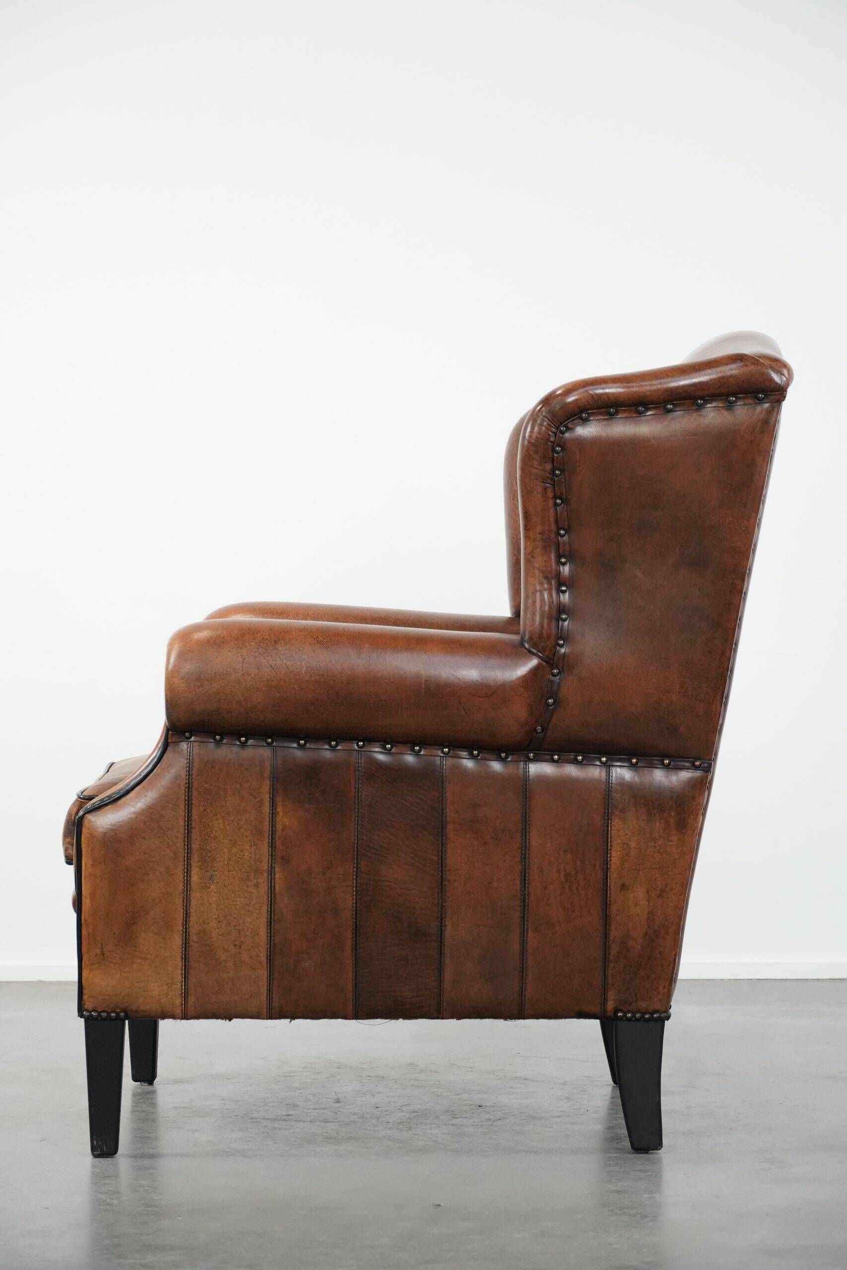 Sheepskin wingback armchair with decorative nails and black piping