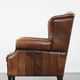 Sheepskin wingback armchair with decorative nails and black piping