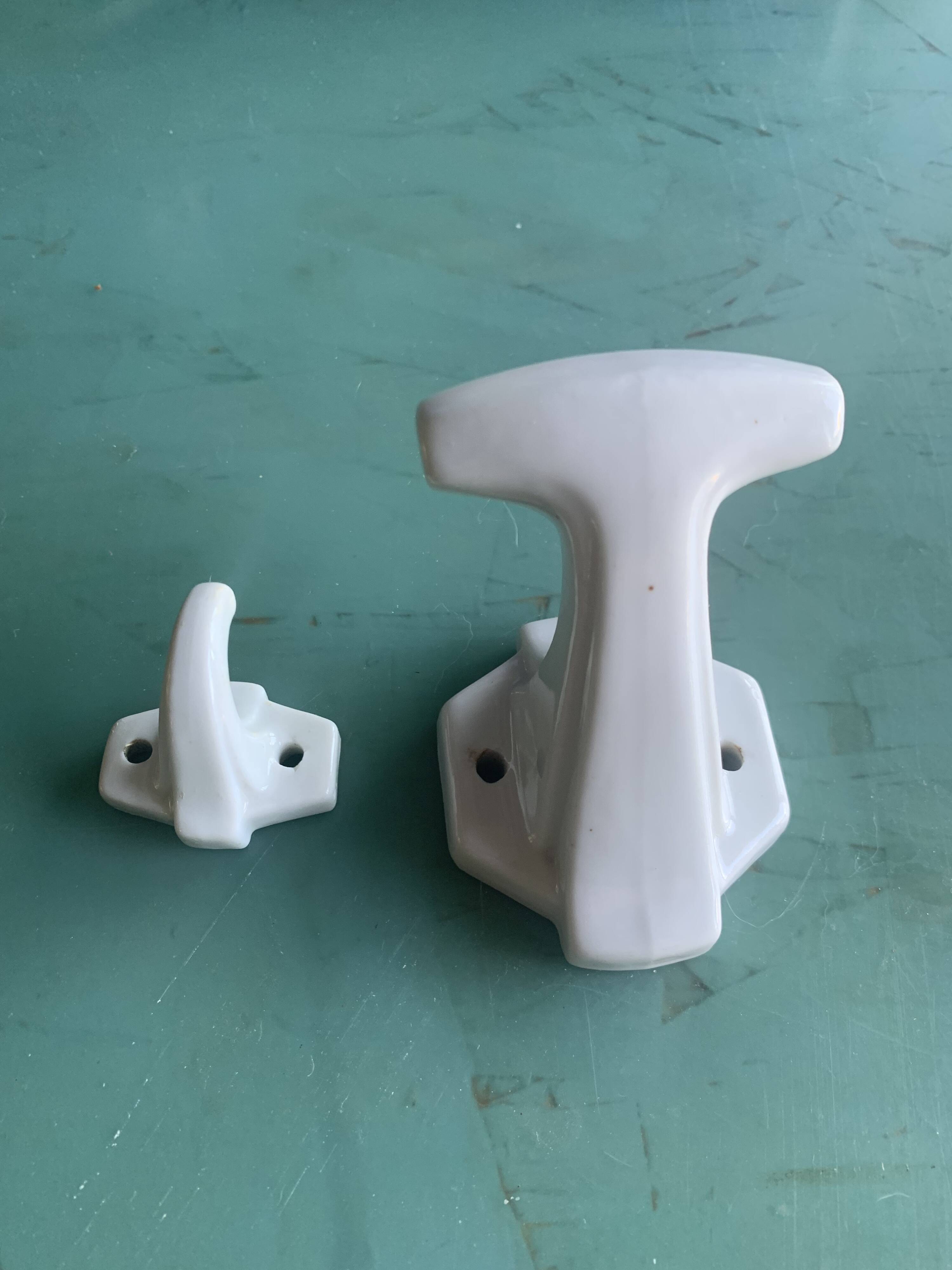 Two white porcelain coat hooks, one small and one larger, old