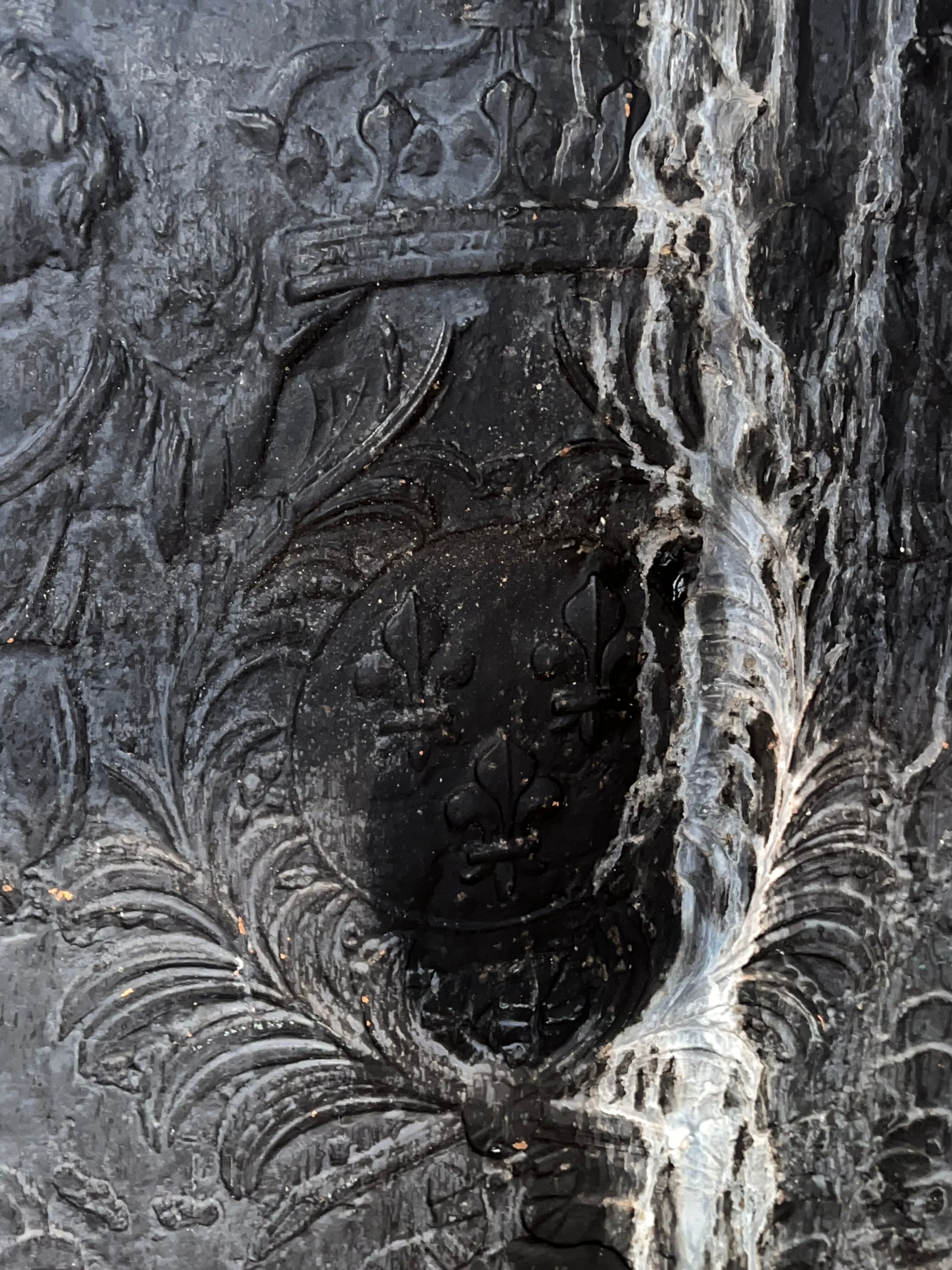 huge old fireplace plate has decoration of angels, crown and fleurs-de-lis