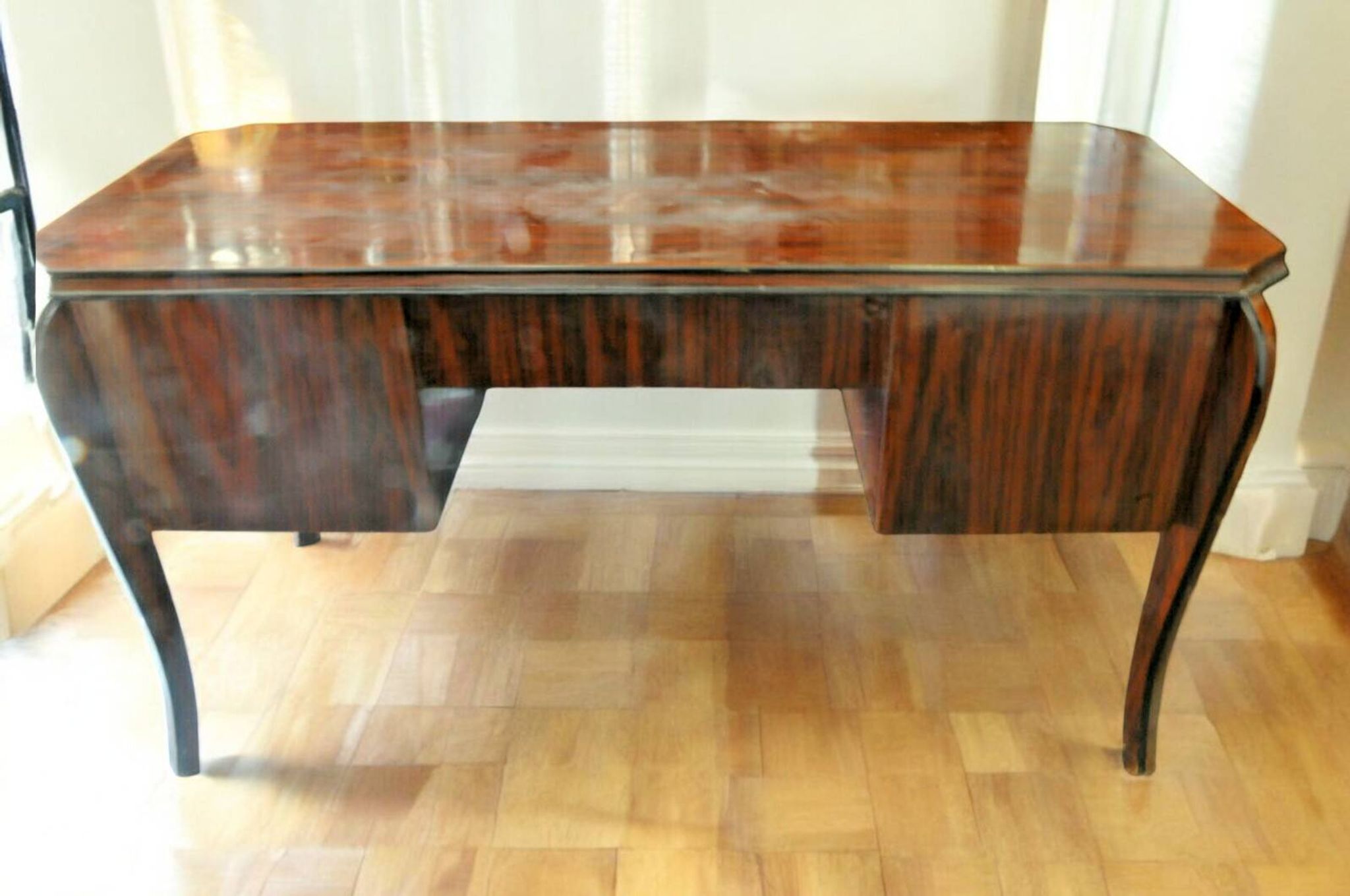 A large Art Deco style rosewood desk with 5 drawers and decorative motifs