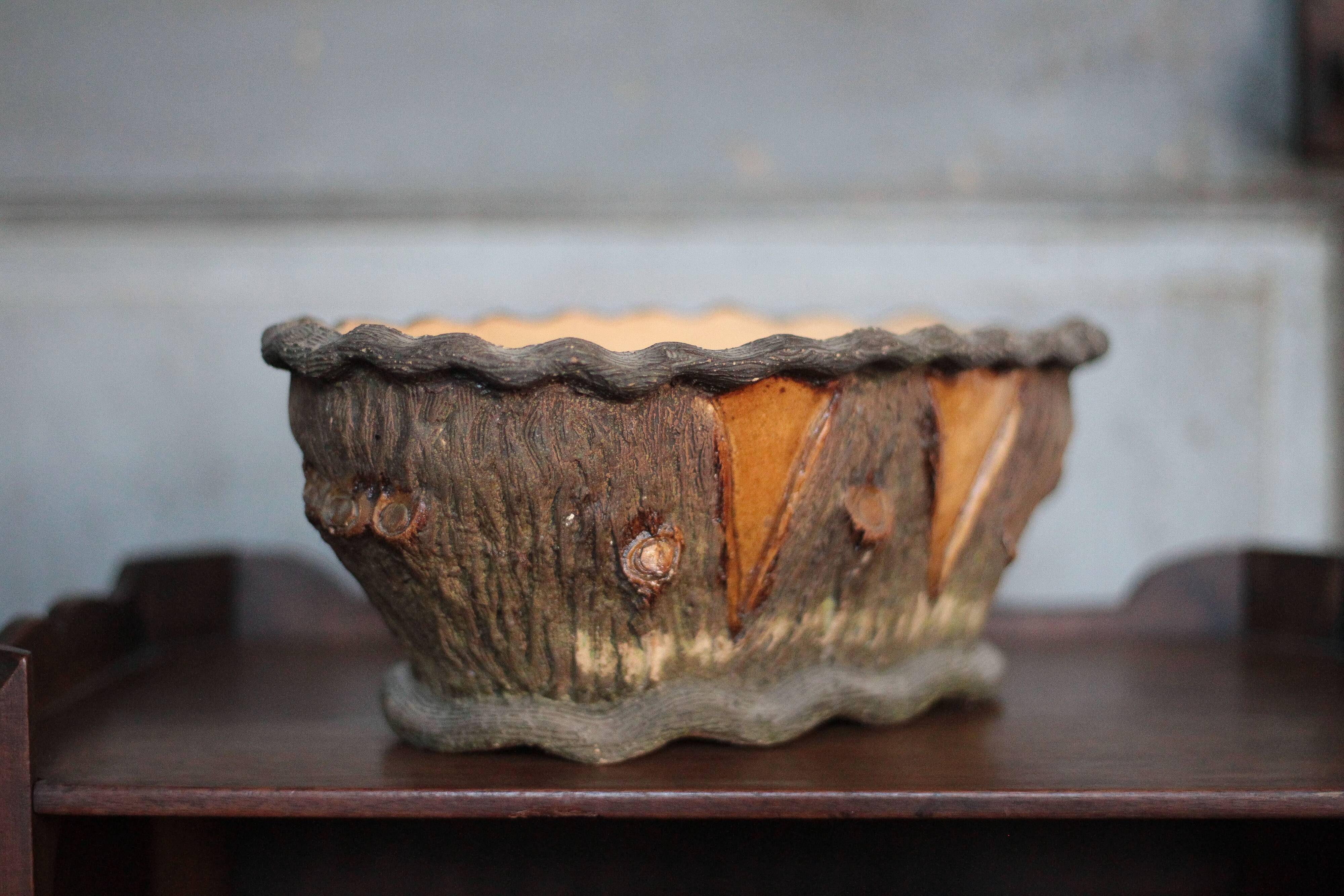 Terracotta planter in a brutalist style resembling a tree trunk, pot cover, countryside.