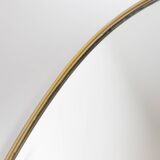 Oval shaped mirror set with a gilded brass rod. 1970s.