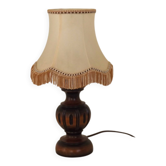 Mid-century French table lamp made of turned carved wood with a fringed shade.