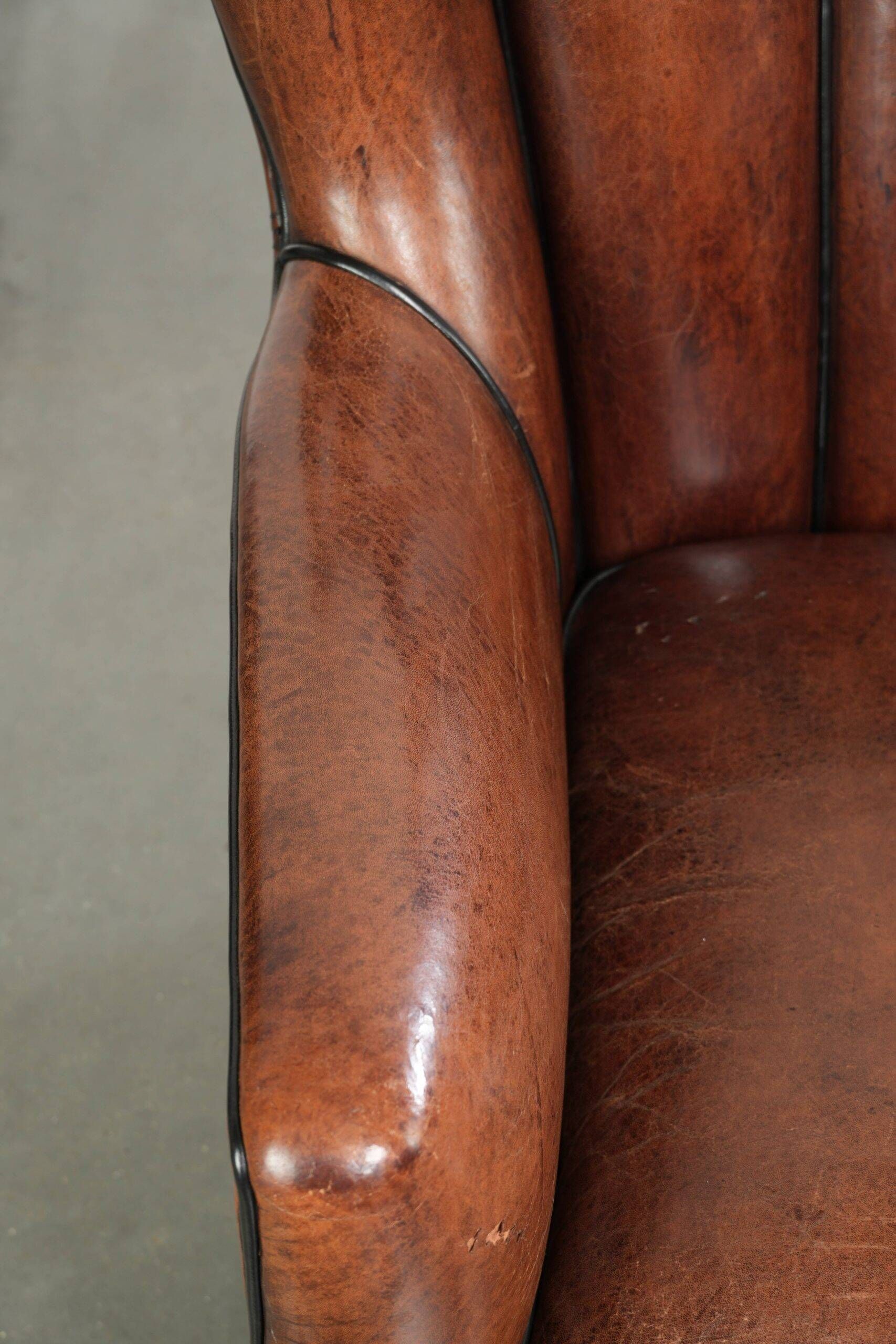 Fauteuil en peau de mouton confortable au design unique, fini avec un passepoil noir.