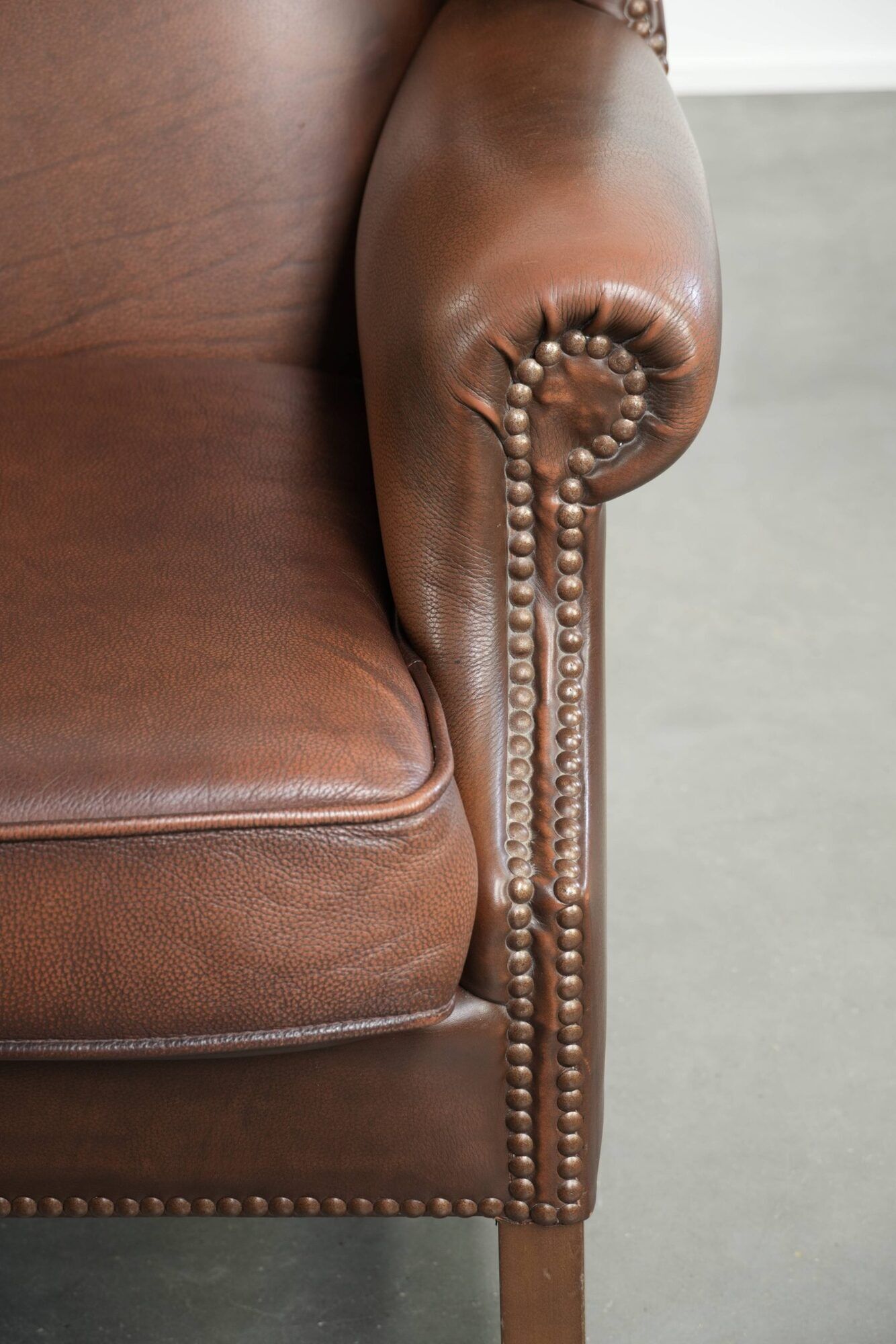 Cowhide wingback armchair in English style finished with decorative nails